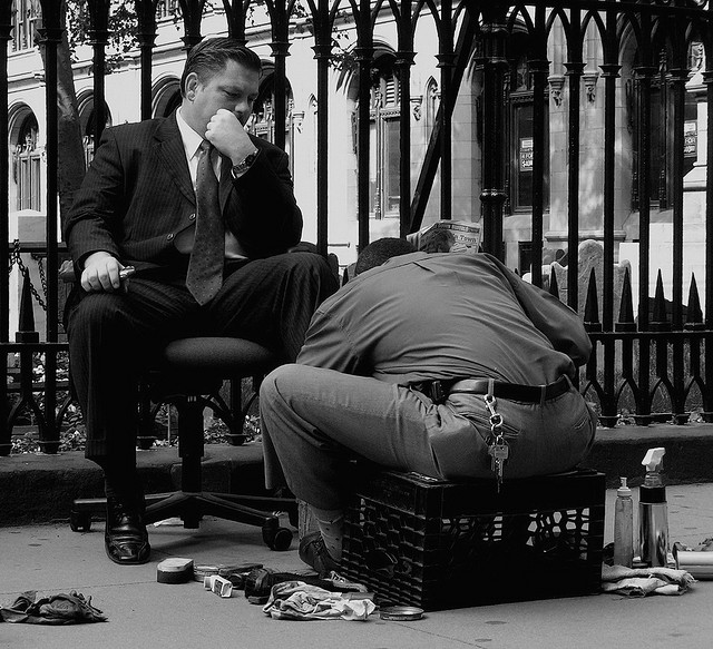A photo of a business man having his shoes shined.
